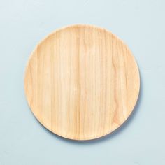 a wooden plate sitting on top of a blue table next to a white and gray wall