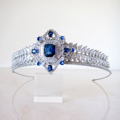 Be bold in blue!  This regal, handmade showstopper is silver plated and encrusted with cubic zirconia crystals.  Attach to the head by stringing provided elastic ribbon through loops at the back. Heigh at centre: 5cm  Width: 15cm Regal Wedding Headpiece With Structured Crown, Regal Structured Crown Wedding Headpiece, Regal Structured Crown Headpiece For Wedding, Regal Tall Crown Headpieces For Wedding, Silver Headband Crown For Wedding, Luxury Wedding Crown Jewelry, Wedding Teardrop Crown Headpiece, Regal Tall Crown For Wedding, Silver Crown Headpiece For Wedding