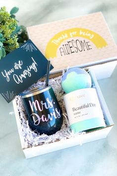 a gift box with a candle, mug and some other items in it on a table