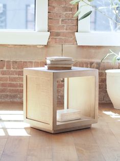 a wooden table with books on it in front of a brick wall and potted plant