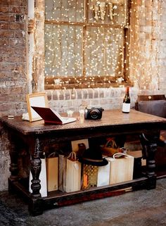 an old table with books and other items on it in front of a brick wall