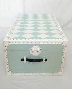 an old blue and white checkerboard suitcase sitting on top of a white table