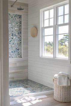 a bathroom with white walls and wood flooring next to a large window that looks out onto the ocean