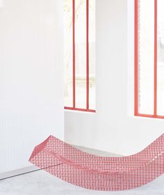 a red piece of cloth sitting on top of a white floor next to two windows