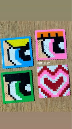 four square coasters that have different designs on them, one has an eye and the other has a heart