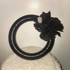 there is a black ring with flowers on top of the white snow covered rock in front of a wall