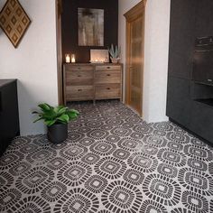 a black and white tiled floor in a room with wooden cabinets, drawers and a potted plant