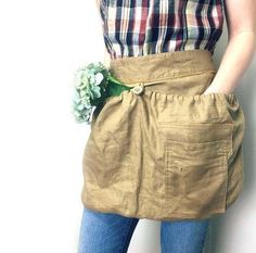 a woman wearing a tan skirt with a flower in her pocket and jeans on the bottom