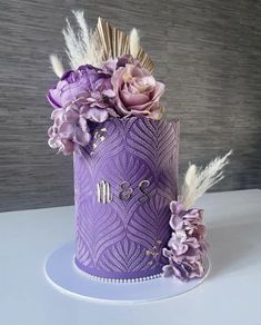 a purple cake decorated with flowers and feathers