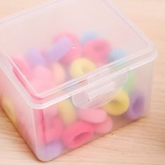 a plastic container filled with colorful beads on top of a wooden table