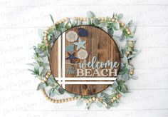 a wooden sign that says welcome to the beach with shells and leaves around it on a white brick wall