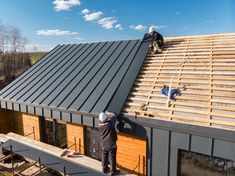 two men are working on the roof of a house that is being built with metal sheets