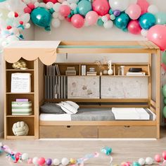 a bunk bed with a desk underneath it and balloons in the air behind it for decoration