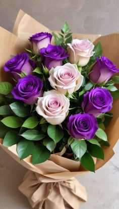 a bouquet of purple and white roses wrapped in brown paper