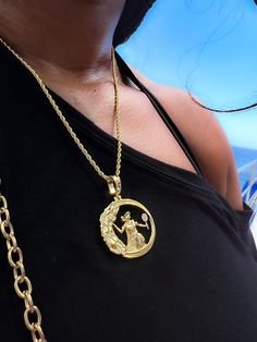 a woman wearing a gold necklace with an image of a man holding a baby on it