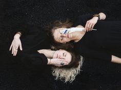 two women laying down on the ground with their hands over each other's eyes