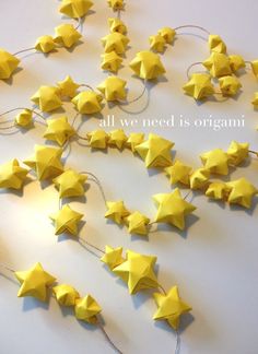 some yellow stars are hanging from string on the table with words all we need is origami