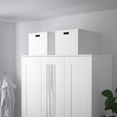 three white boxes are sitting on top of each other in the corner of a room