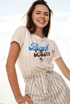 "The \"Beach Bum Shirt with Sun at the Bottom\" is not only visually appealing but also versatile in its styling options. Pair it with your favorite denim shorts or a flowy skirt for a laid-back beach-inspired look. Dress it up with a pair of linen trousers and sandals for a chic and casual evening out. The possibilities are endless, allowing you to express your personal style with ease. Whether you're strolling along the shoreline, enjoying a beachside bonfire, or simply soaking up the sun's rays, this shirt will make you feel like a true beach bum. It's a fantastic choice for beach lovers, summer enthusiasts, or anyone looking to add a touch of coastal charm to their wardrobe." Casual Pre-shrunk T-shirt For Beach, Casual Short Sleeve Top For Beach Season, Relaxed Short Sleeve T-shirt For Vacation, Casual Cotton Tops For Beach Season, Casual Crew Neck T-shirt For Vacation, Summer Cotton T-shirt For Beach Party, Summer T-shirt With Text Print For Day Out, Relaxed Fit Summer T-shirt For Beach Party, Relaxed Fit Summer T-shirt