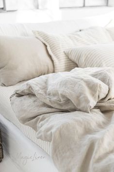 an unmade bed with white sheets and pillows