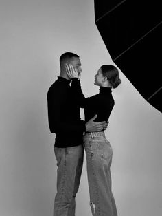 a man and woman standing next to each other in front of a black and white photo