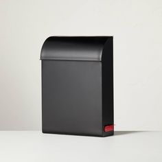 a black mailbox sitting on top of a white table next to a red box