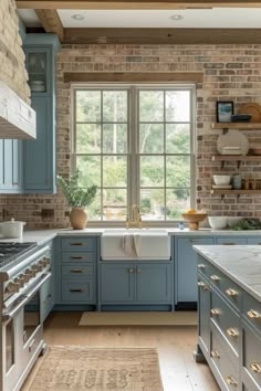 a kitchen with blue cabinets and white counter tops in front of a large brick wall