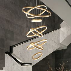 a modern chandelier hanging from the ceiling in a lobby with marble walls and stairs