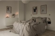 a large bed sitting in a bedroom next to two pictures on the wall and candles