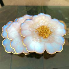 a white flower sitting on top of a table next to a black surface with gold flakes