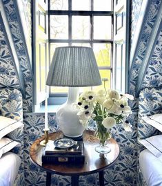 a room with blue and white wallpaper has a lamp on the table next to it