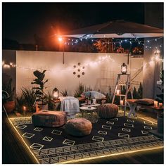 an outdoor area with lights and furniture on the ground, surrounded by potted plants