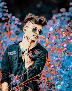 a man wearing sunglasses standing in front of some flowers