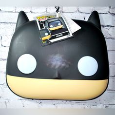 a black and yellow cat shaped object with white dots on it's eyes, sitting against a brick wall