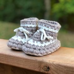 a pair of crocheted baby shoes sitting on top of a wooden bench