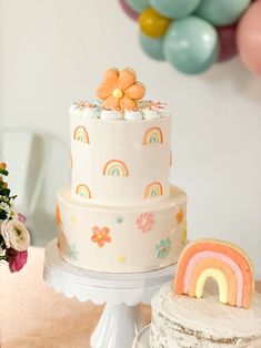 a three tiered cake sitting on top of a table next to balloons and flowers