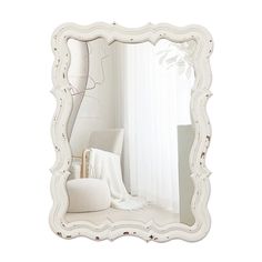 a white mirror sitting on top of a table next to a chair and window sill