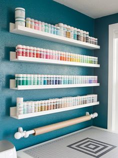 the shelves are filled with different colors of paint and crafting supplies in this bathroom