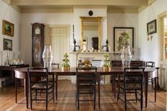 a dining room table and chairs in front of a mirror with an ornate clock on the wall