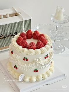 a white cake with raspberries on top sitting on a table next to an amp