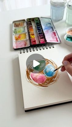 a person is painting with watercolors on a notebook