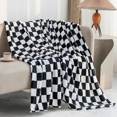 a black and white checkered blanket sitting on top of a couch next to a lamp