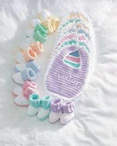 several crocheted baby booties are laid out on a white sheet with the word welcome