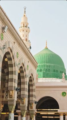 an ornate building with a green dome in the middle and white columns on both sides