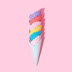 an ice cream cone with multicolored waffles sticking out of it on a pink background