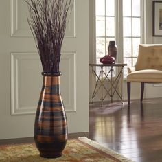 there is a vase with some plants in it on the floor next to a chair