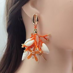 Brighten up your look with these Orange and White Coral Stud Earrings, expertly handcrafted from Japanese Delica beads. Each earring features detailed beaded coral branches and intricately beaded starfish in vibrant orange and crisp white tones. Enhanced with genuine seashells and 18K gold-filled accents, these earrings radiate both luxury and natural beauty. The 18K gold-filled stud closures, designed as delicate seashells, add a sophisticated finishing touch. Ideal for beach lovers and those w Orange Drop Earrings For The Beach, Orange Drop Earrings For Beach, Orange Dangle Jewelry For Beach, Unique Beaded Drop Earrings For Beach, Beach Earrings With Dangling Beads, Handmade Beaded Earrings For Beach, Coral Beaded Drop Earrings, Bohemian Colorful Beads Earrings For Vacation, Bohemian Beaded Dangling Earrings For Vacation