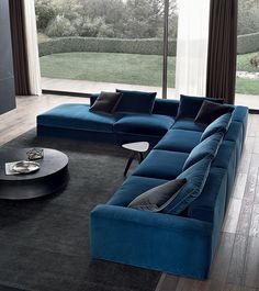 a blue sectional sofa sitting in front of a large window with a black rug on top of it