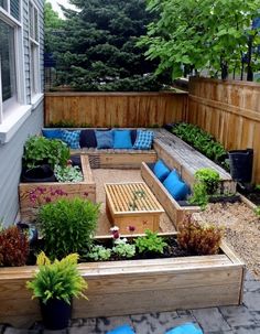 a backyard garden with wooden planters and blue cushions