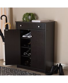 an open cabinet with shoes and umbrellas on it in front of a window next to a rug